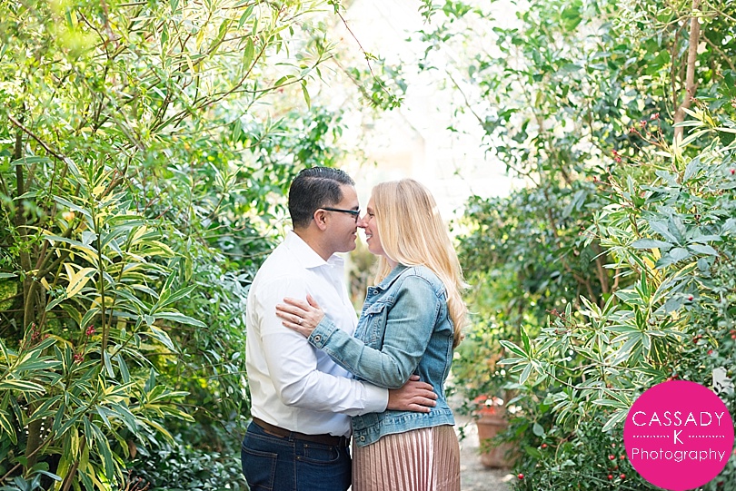 Couple looking at each other surrounded by plants in a greenhouse during a Stonecrop Gardens Engagement Session