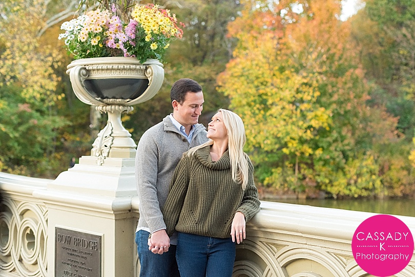 Engaged Couple looking at each other on the Bow Bridge for a Central Park Fall Engagement Session in NYC
