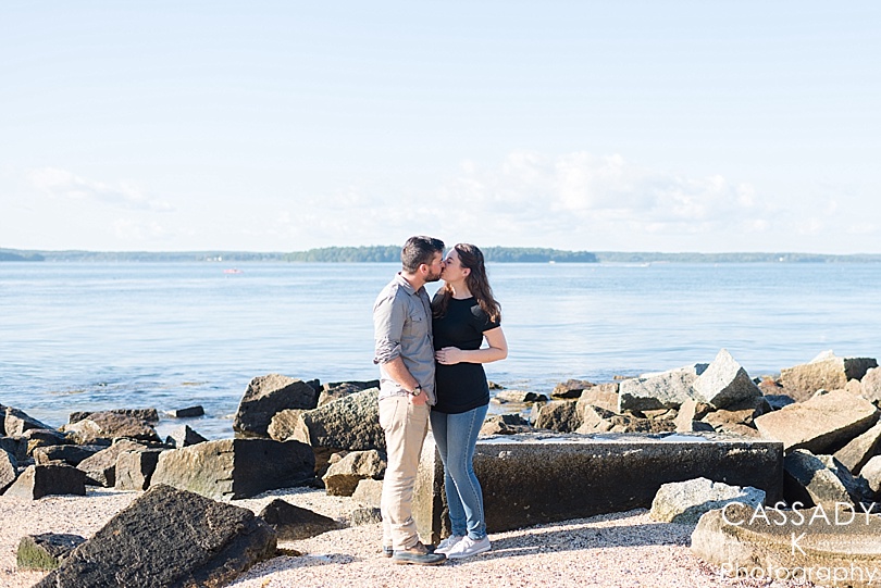 Couple on the beach looking over Casco Bay during a Fort Gorges Maternity session in Portland, Maine
