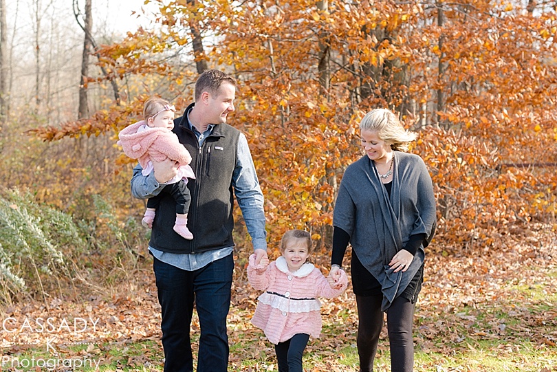 Family with two little girls walks in changing leaves during a Leonard Park Fall Family Portraits in Westchester County, NY