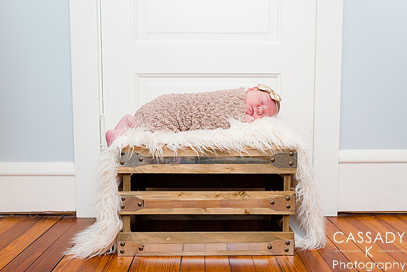 Baby girl lays on top of fur on a crate during a PA Family Newborn Session at home in Lansdale