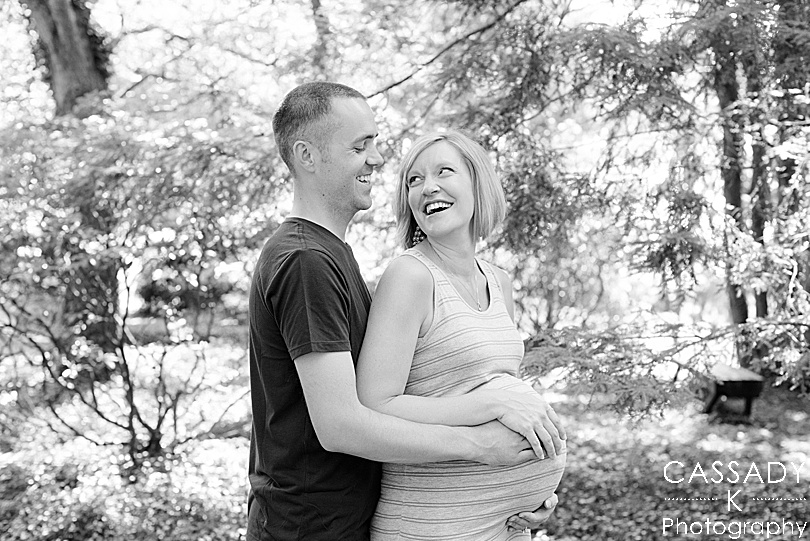 Black and white of a husband and wife laughing during their outside family maternity session