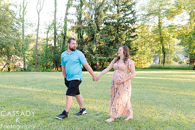 Dad and Pregnant Mom walk through a field during a Pittsburgh Maternity Session