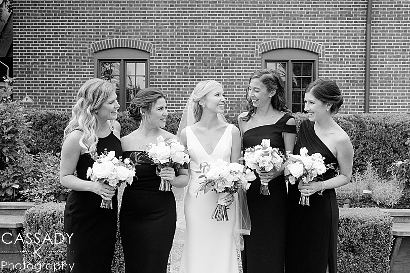 Bridesmaids talking to each other in front of brick building during a Small Ninety Acres Wedding in Natirar of Peapack, NJ