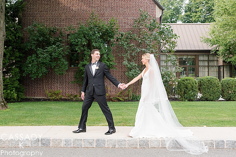 Bride and Groom walking in front of brick building during a Small Ninety Acres Wedding in Natirar of Peapack, NJ