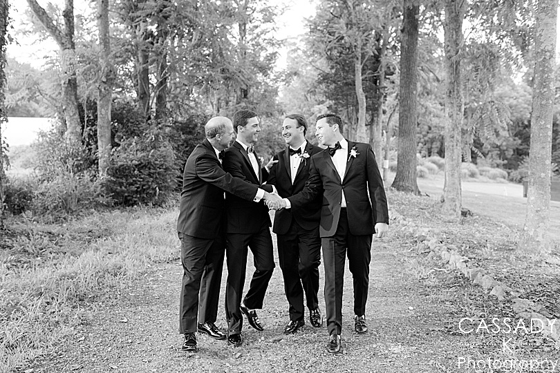 Groomsmen walk down a grove of trees during a Small Ninety Acres Wedding in Natirar of Peapack, NJ