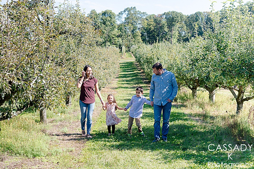 Tips for Family Photos from a family walking through an apple orchard at Frecon Farm doing Fall activities in PA