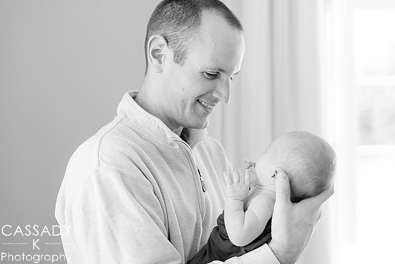 Black and white of a father holding his son and looking at him during an at home Bedford newborn session in Hudson Valley, NY