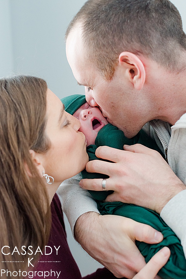 Mom and Dad kiss baby boy on his cheeks during an at home Bedford newborn session in Westchester County, NY