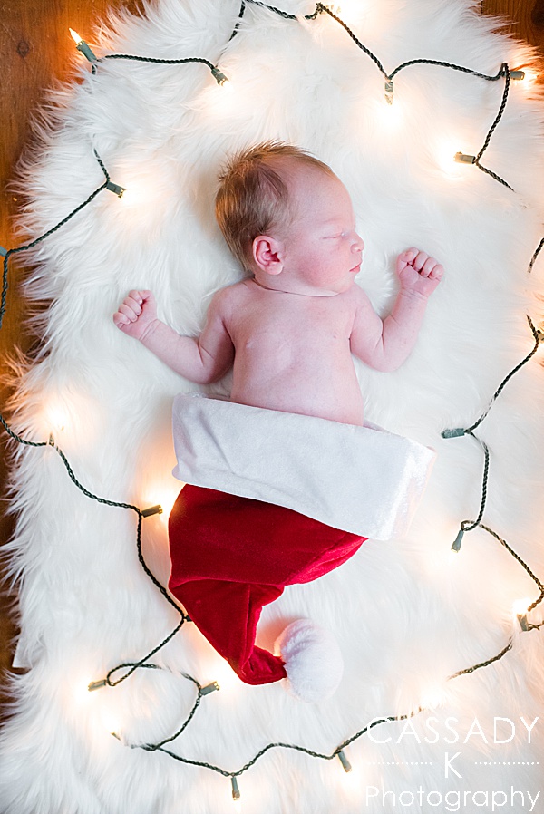 Newborn boy in a Santa hat on a white fur with Christmas lights around baby in Pittsburgh, PA for a 2020 photography review