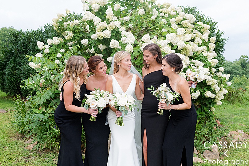 Bridesmaids laughing in front of a hydrangea bush at a small outside Ninety Acres wedding during a 2020 photography review