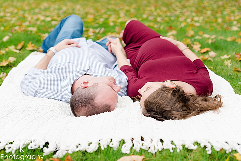 Parents lay on a blanket outside at a home autumn maternity session in Hudson Valley, NY for a 2020 photography review