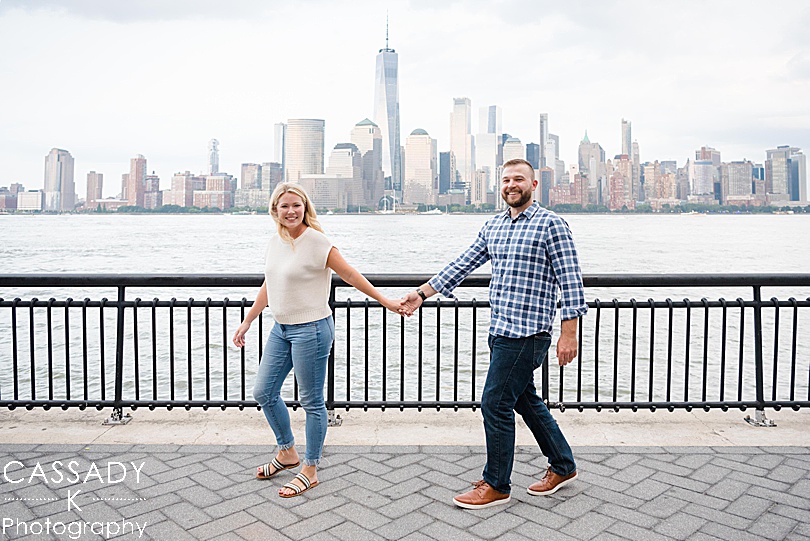 Engaged couple walks along the Hudson River during a Jersey City Engagement Session in NJ