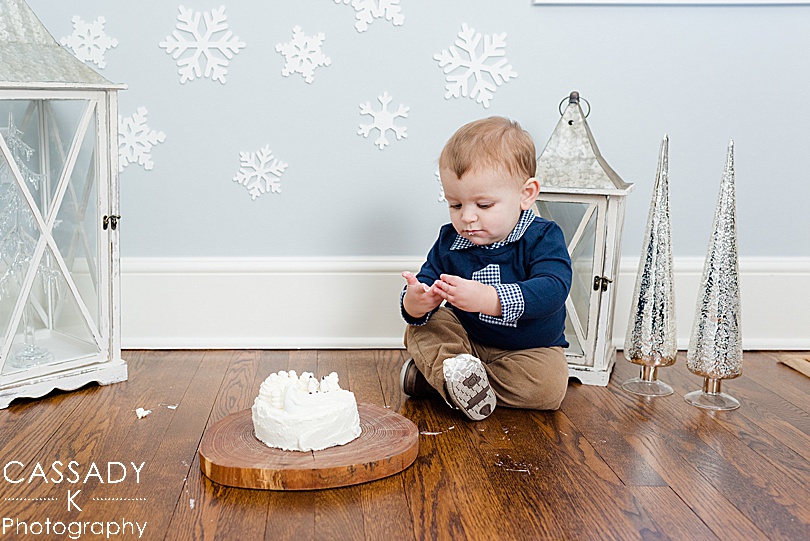 One year old has a cake smash during his at home first birthday pictures in his Winter Onederland in Bedford, NY