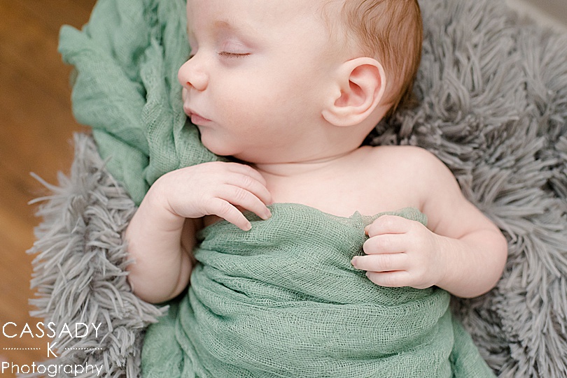 Baby boy laying in basket asleep with green gauze fabric over him during Bellefonte Home Newborn Pictures in Centre County