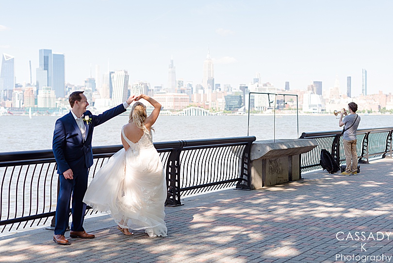 Bride and groom twirling on Pier A with NYC skyline in background before their Antique Loft Hoboken Wedding