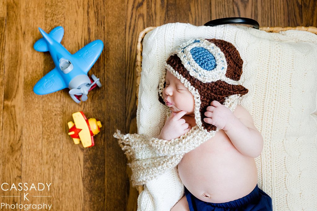 Newborn baby boy posed in crocheted aviator pilot hat and scarf in Westchester County New York
