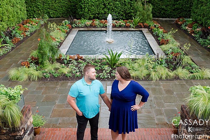 Future bride and groom standing on steps in front of fountain at Longwood Gardens during their Engagement Photos