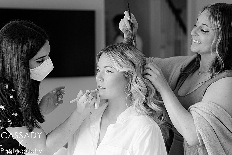 Makeup and hair artist putting final touches on bride before wedding