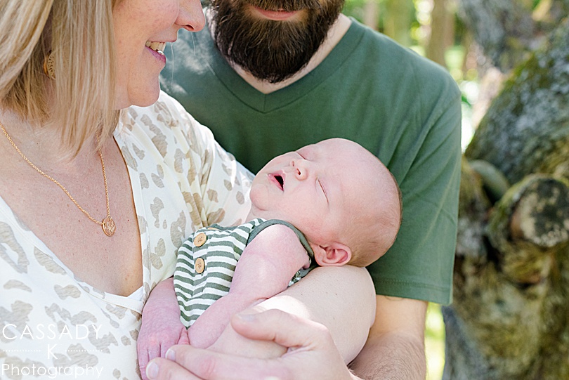 Picture of baby boy in mom and dads arms in spring outside