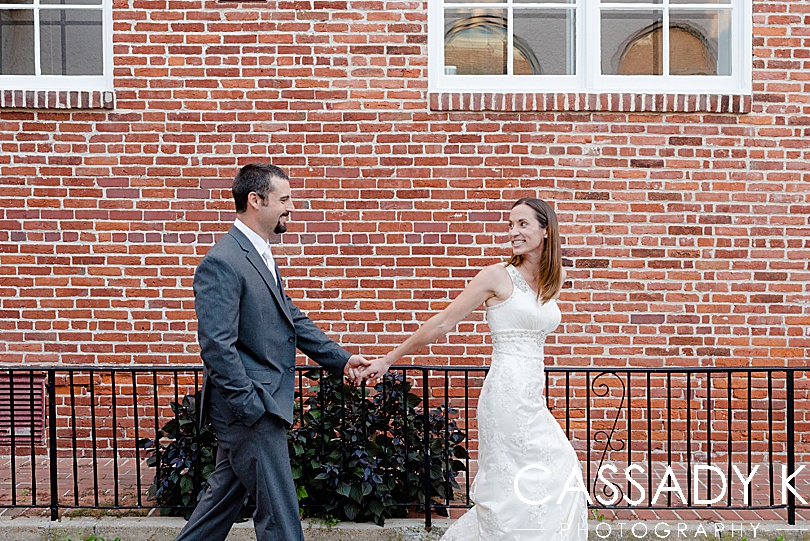 Husband and wife walking along a brick building during their 5th wedding anniversary photos