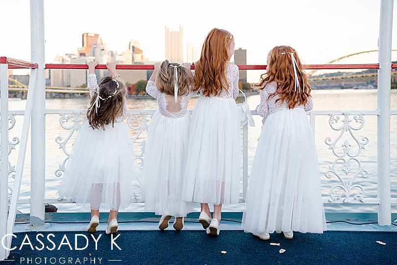 Flower girls standing at edge of boat looking over water