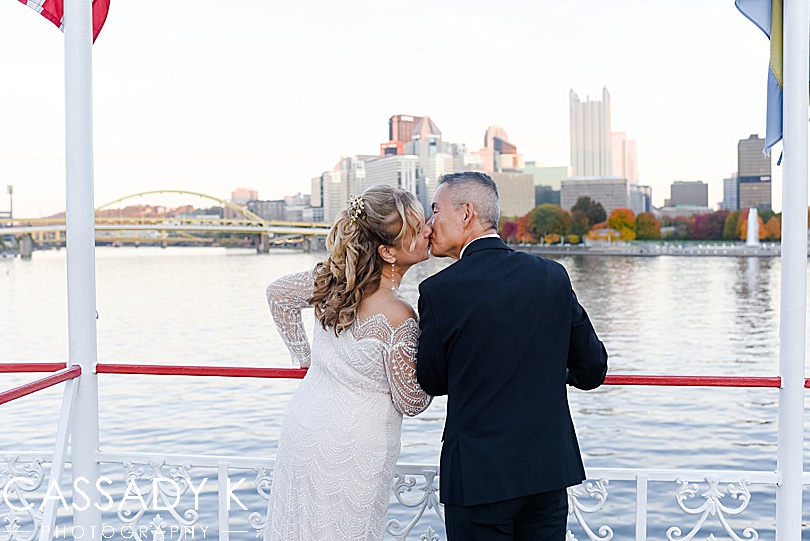 Bride and groom kissing with Pittsburgh Pennsylvania in the background during fall Gateway Clipper wedding
