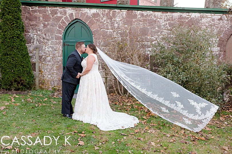 Groom and bride kissing in front of green door at Mount Hope Estate Wedding
