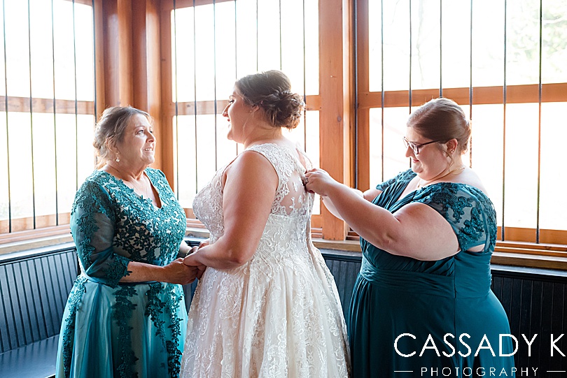 Mom and sister in teal dresses helping bride get dress on at Mount Hope Estate Wedding