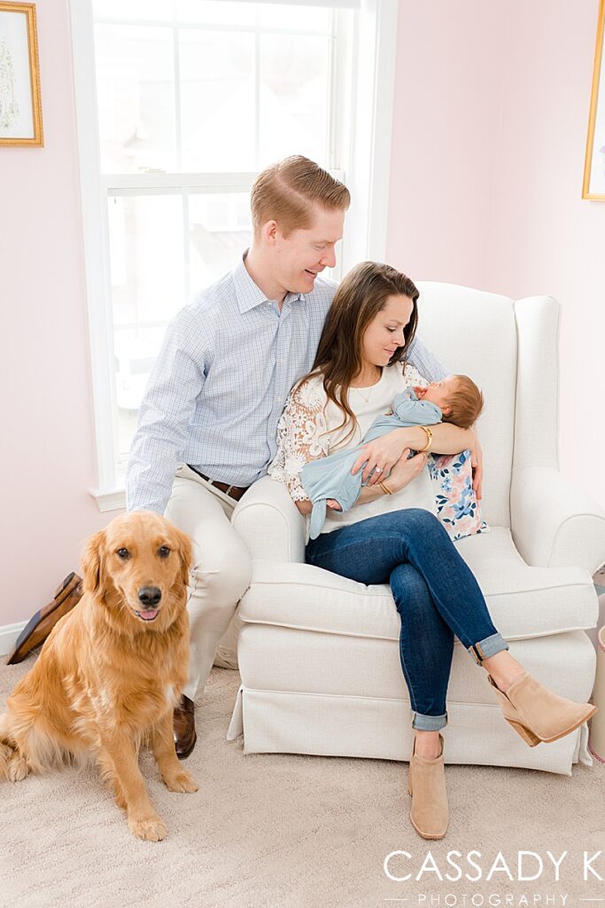 Family picture with their golden retriever in the baby girl's pink nursery.