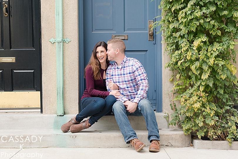 Couple sitting on step in front of blue door on Washington Mews on NYU's campus during Greenwich Village Engagement Session in NYC