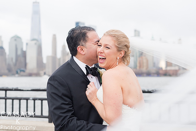 Bride laughs as groom kisses her in front of the New York City skyline for my favorite wedding pictures of 2018