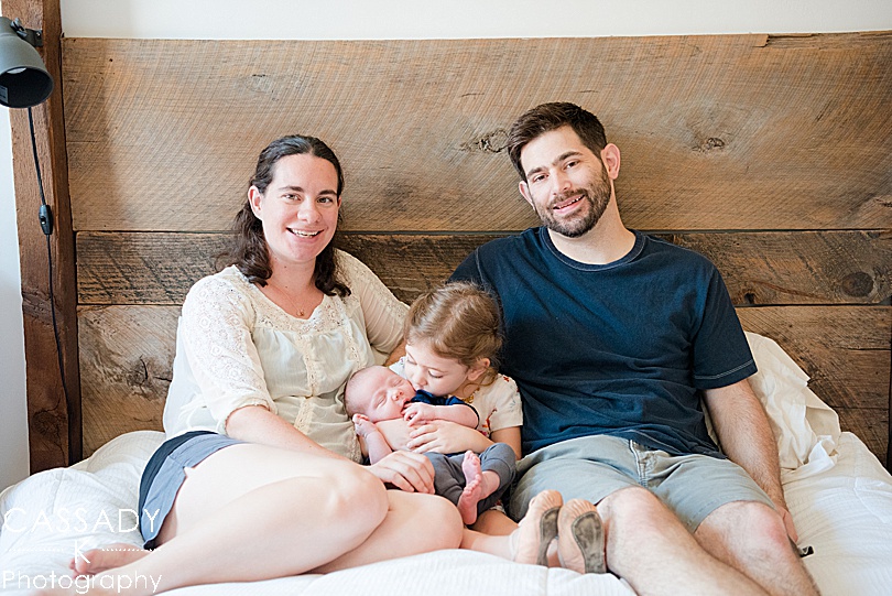 Family of four with new baby boy in rustic bed for a Pittsburgh Family Newborn Session