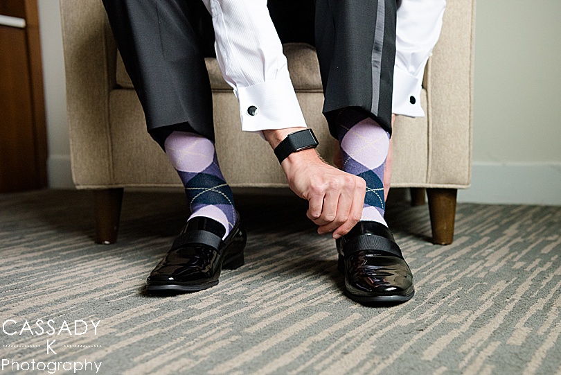 Groom putting on shoes while wearing purple argyle socks for a Small Ninety Acres Wedding in Natirar of Peapack, NJ