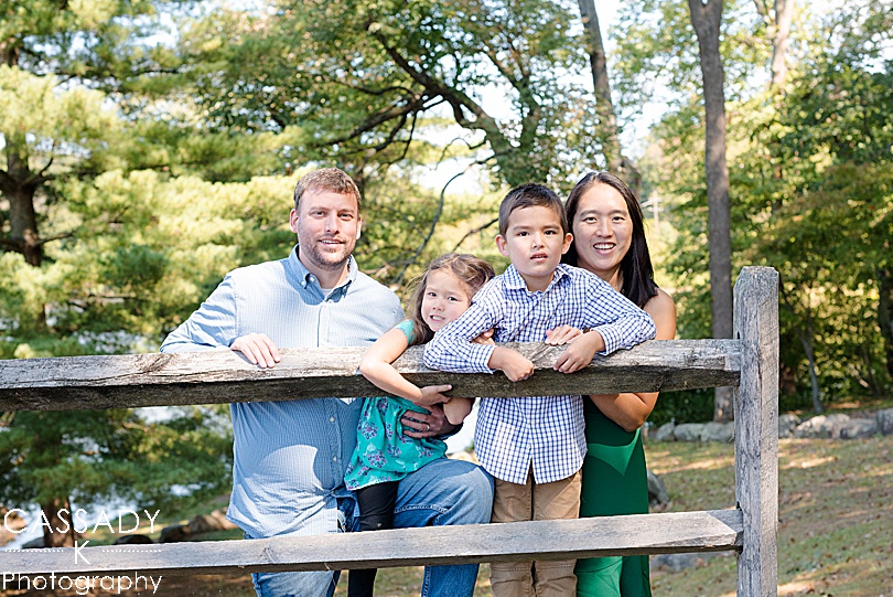 Tips for Family Photos from family leaning on a fence outside during Fall activities in PA