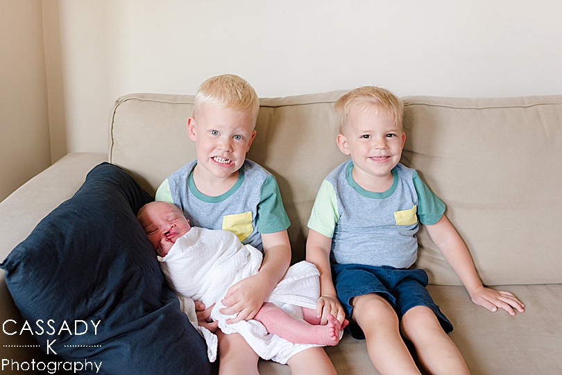 Big brother hold their baby brother on the couch at home Williamsport Newborn Session in PA