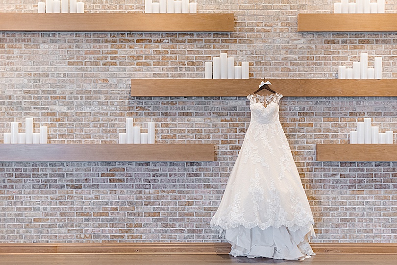 The bride's dress hanging on floating shelves in the ballroom with candles for a Mansion at Natirar Wedding in Peakpack