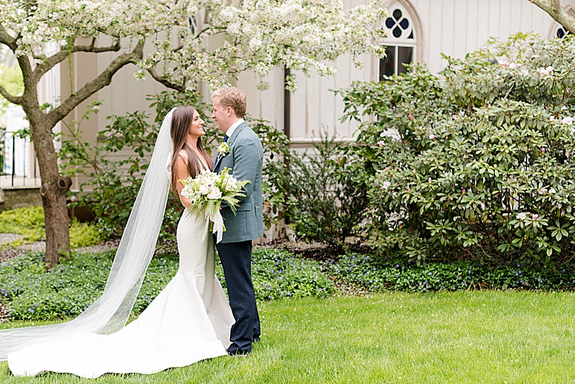 Bride and Groom under the white flowering trees at Trinity Episcopal Church in Southport, CT during the Tokeneke Club Wedding