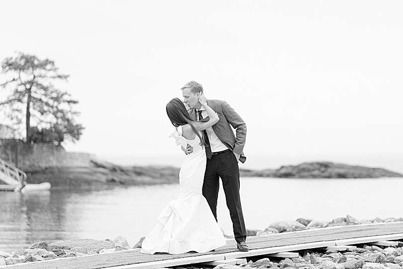 Black and white of Groom kissing his Bride along the water at a Tokeneke Club Wedding reception in Darien, CT