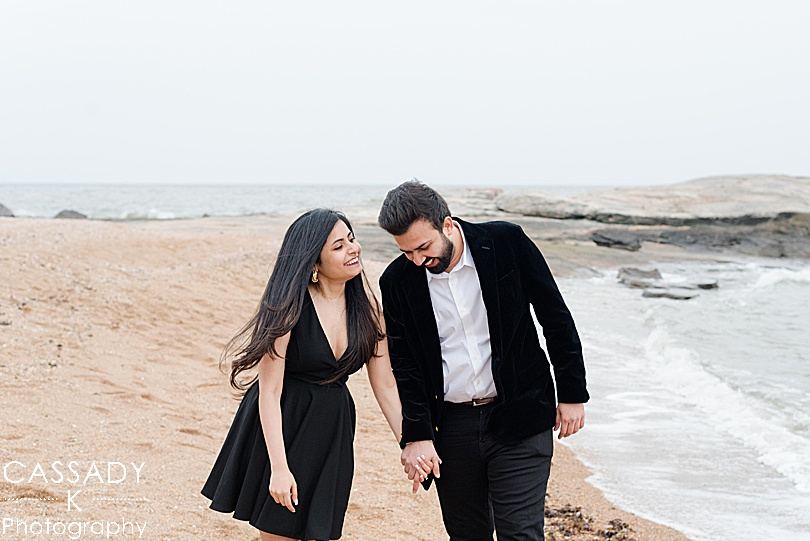 Newly engaged couple laughs and walks along the beach after a Madison Beach engagement proposal