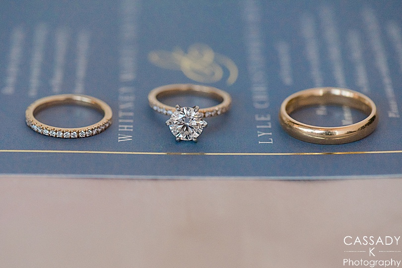 Engagement and wedding rings on top of navy invitation suite for their Antique Loft Hoboken Wedding