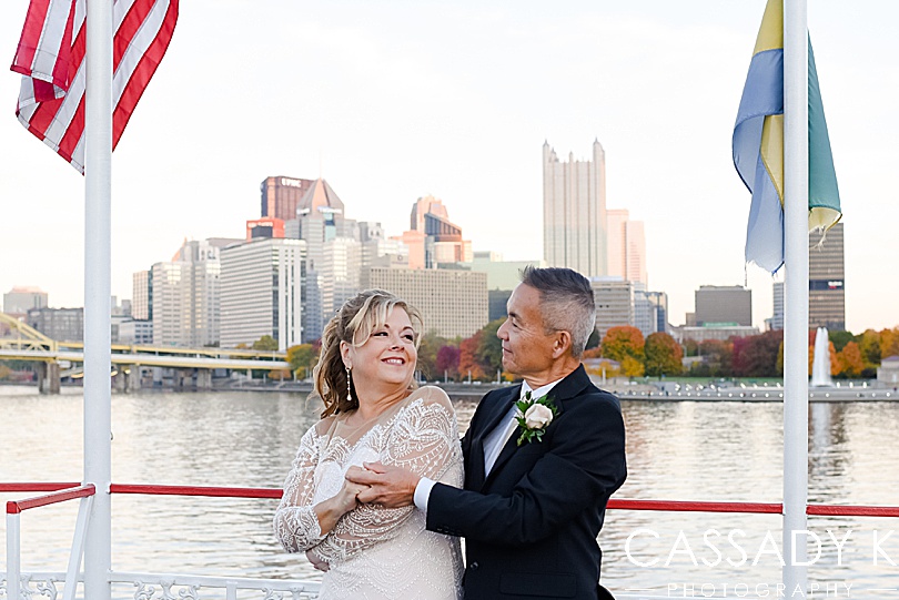 Bride and groom in front of Pittsburgh on water for fall Gateway Clipper wedding
