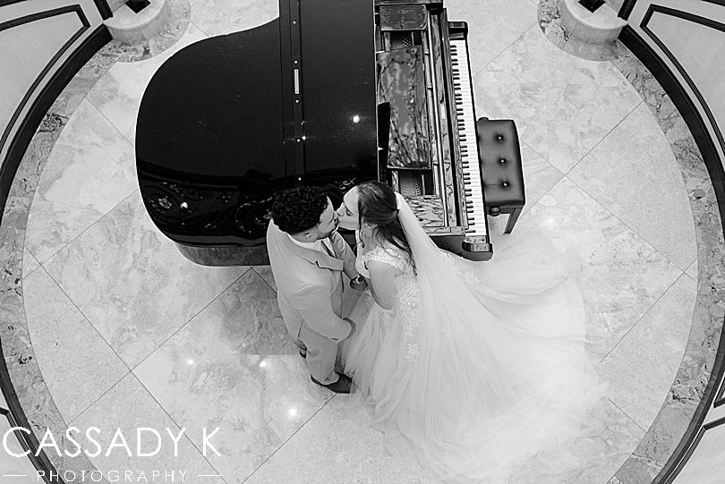 Black and white photo of bride and groom by piano at Surf Club on the Sound wedding