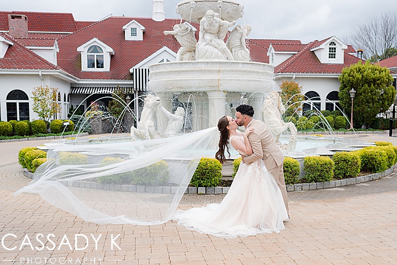 Bride and groom kissing in front of fountain at Surf Club on the Sound wedding