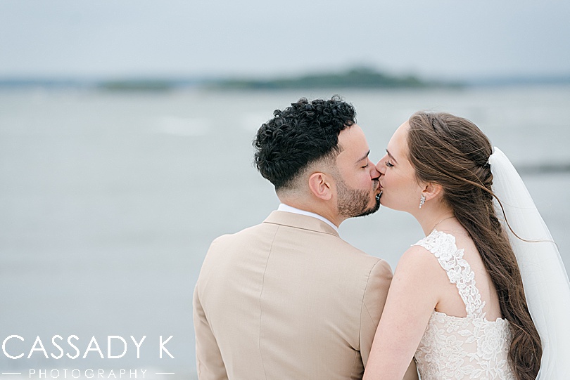 Bride and groom kissing by waterfront for Surf Club on the Sound wedding