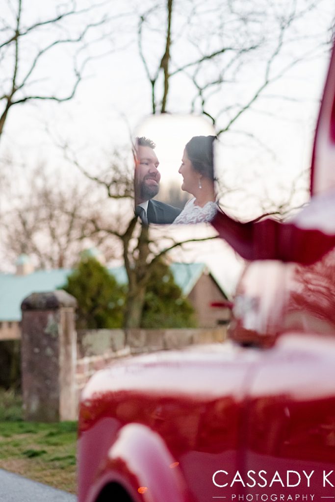Bride and groom looking at each other in car mirror