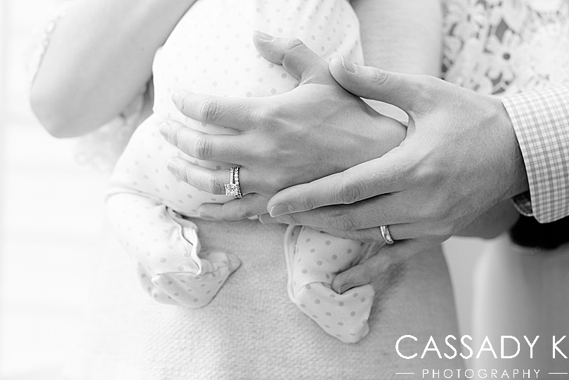 The parents' hands holding their baby and showing their wedding bands in Doylestown PA newborn pictures