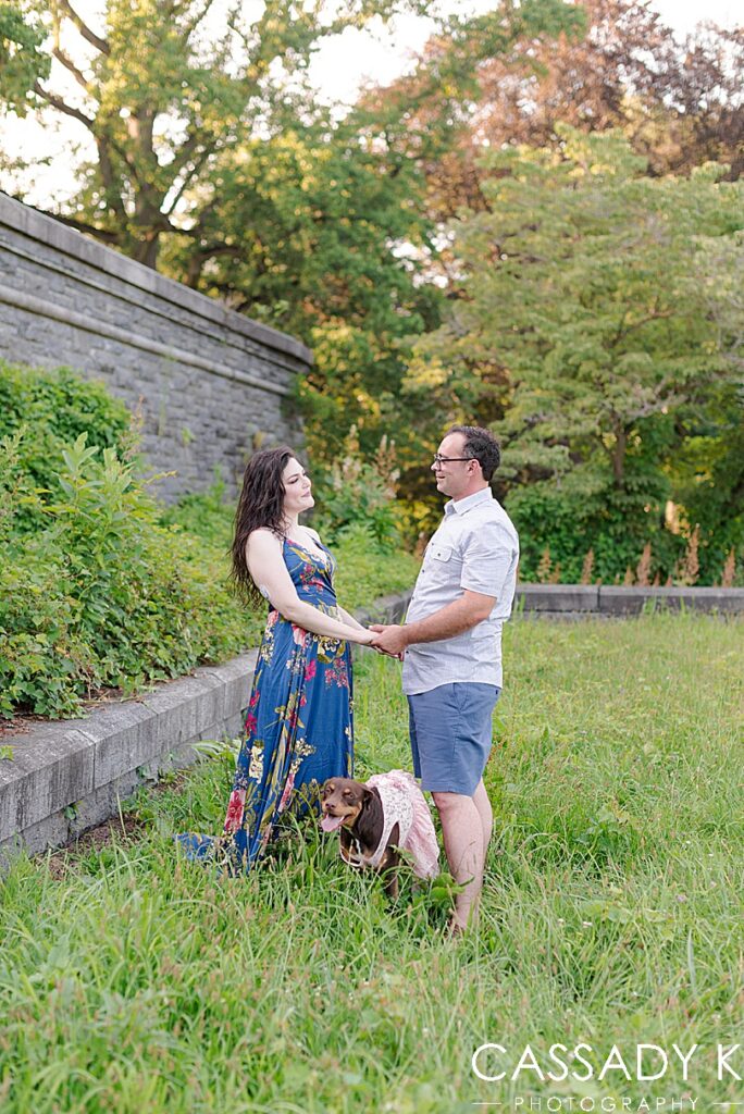 Man and woman holding hands and looking at each other in field during Rockwood Hall engagement photos