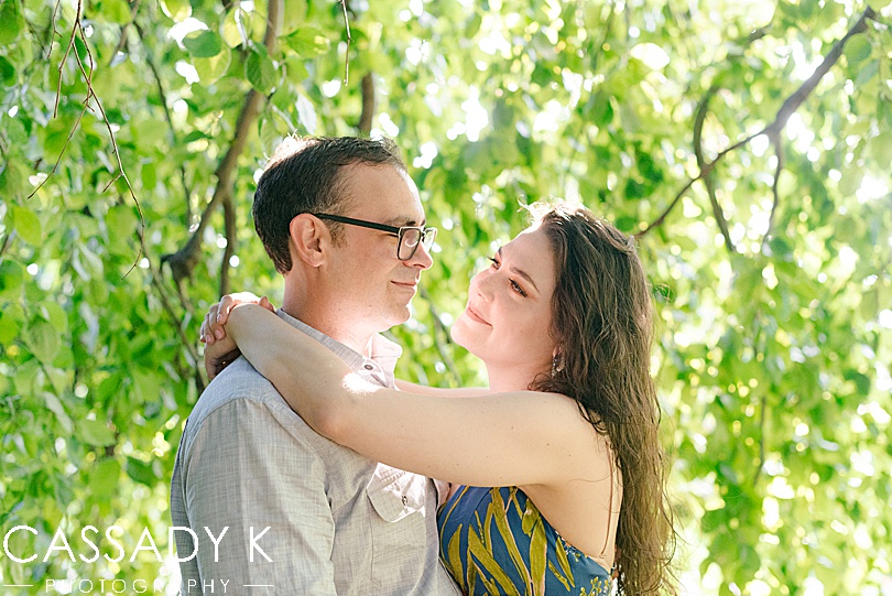 Man and woman looking at each other under willow tree during Rockwood Hall engagement photos