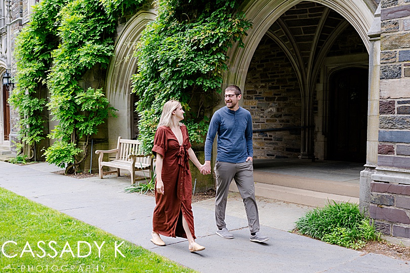 Couple walking next to building in Princeton, NJ engagement session